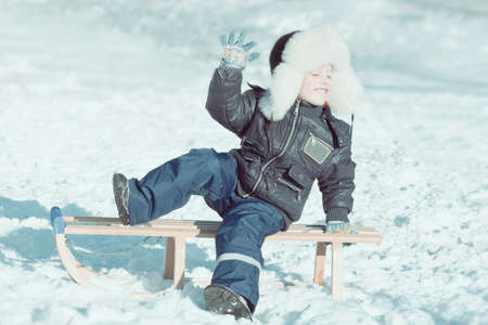 boy on sled with close eyes enjoying winter sun