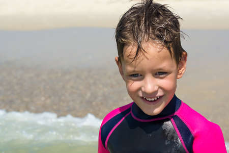 small boy in his diving suit smiling at beachの写真素材
