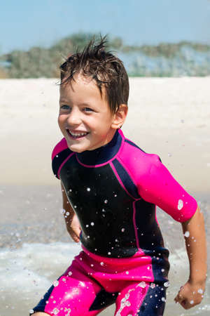 small boy in his diving suit smiling at beachの写真素材
