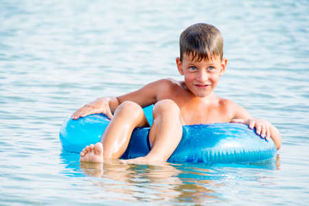 Happy little boy with blue life ring has funの写真素材
