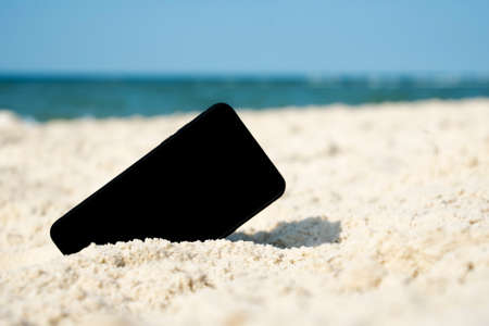 Mobile touch phone in sand on beachの写真素材