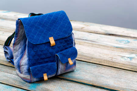 Backpack on wooden pier in waterway on cloudy day.の写真素材
