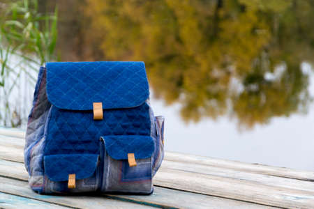 Backpack on wooden pier in waterway on cloudy day.の写真素材