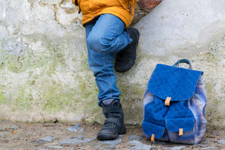 Kid boy legs and backpack against the wallの写真素材