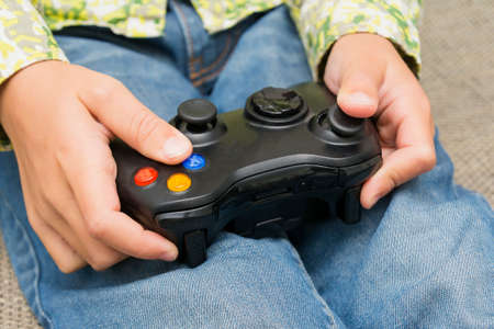 Hands Holding a Joystick Controller while playing a video games at home