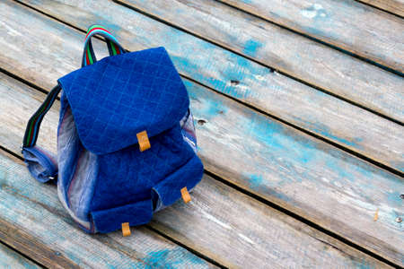 Backpack on wooden pier in waterway on cloudy day.の写真素材