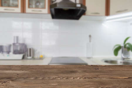 Wooden textured table over blurred kitchen interior background. template for design
