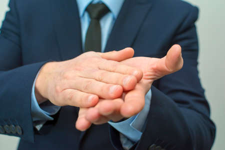 Young businessman in suit rubbing his hands together. emotions and people concept