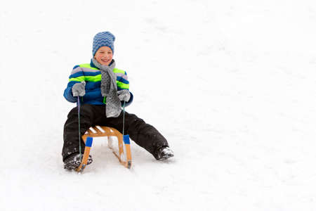 Kid sliding with sledge in the snow.の写真素材