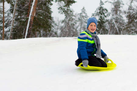 Kid flies down a hill on plate for driving on snowの写真素材
