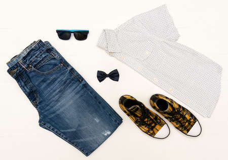 Top view fashion trendy look of kids clothes on white wooden background. Kids fashion.