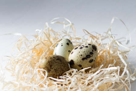 Inscription Happy Easter card with quail eggs on white wooden background.