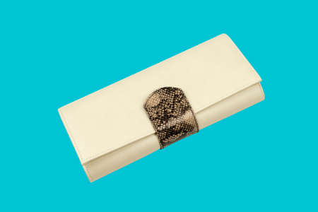 Leather purse on light blue background. Beige clutch with chain inside. Female shoulder bag, close...