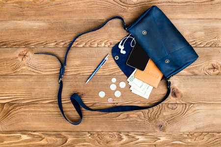 Close up of woman black bag open out with accessories smartphone, passport, earphone and glasses