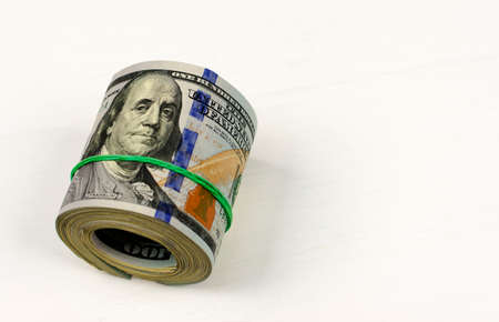 Dollar roll tightened with band. Rolled money isolated on white.