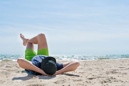 man laying on his back on beach.の写真素材