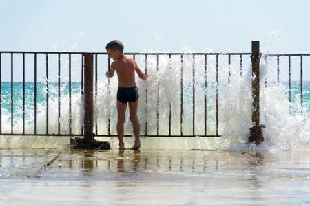 boy playing in the waves off the pierの写真素材