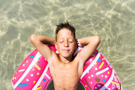 Relaxing boy in inflatable ring in sea.の写真素材