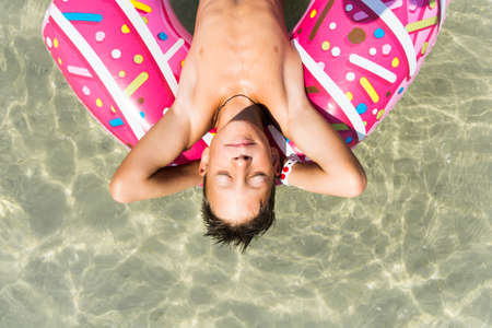 Relaxing boy with inflatable donut in the seaの写真素材