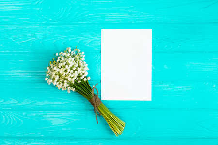 Bouquet of flowers, paper sheet on blue table from above, beautiful vintage card, top view, space...