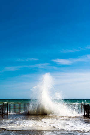 Sea water splashes at old pier on sunny dayの写真素材