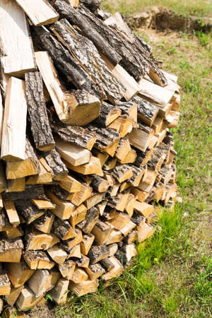 Wooden rectangular firewood for the stove and fire, stacked in a large pile on the outdoor.