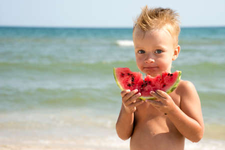 28.08.2018 Lazurne, Ukraine. Cute boy eating watermelon on beachのeditorial素材