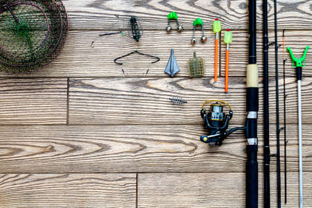 Fishing feeder and reel.Fishing tackle background.Fishing feeder- hooks and lures on darken wooden...