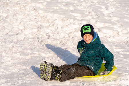 Cherkasy, Ukraine -01.05.2019 Boy sledding down the hills on a winter day.のeditorial素材