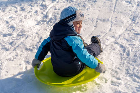 Cherkasy, Ukraine -01.05.2019 Boy sledding down the hills on a winter day.のeditorial素材