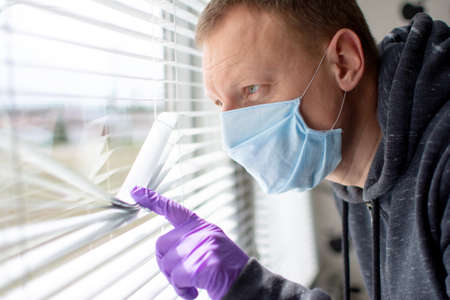 Coronavirus. Sick man of corona virus looking through the window and wearing mask protection .の写真素材