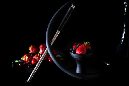 Hookah bowl with berries and on blured dark fruits on dark wood table. Selected focusの写真素材