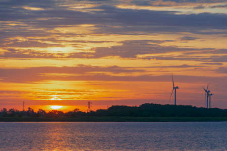 silhouette of wind turbine generating electricity on sunset