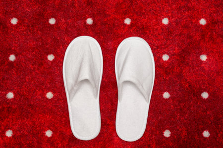White slippers on red carpet with white dots backgroundの写真素材