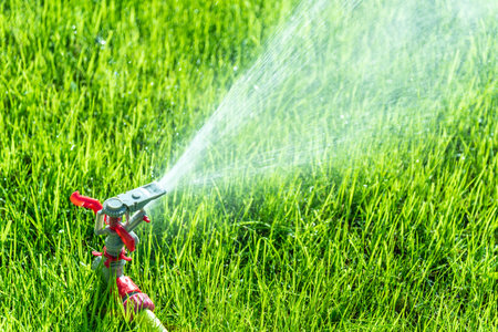 Automatic Garden Lawn sprinkler in action watering grass.の写真素材