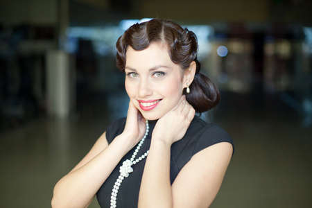 Retro Woman portrait. Young beautiful brunette in black dress looking at cameraの写真素材