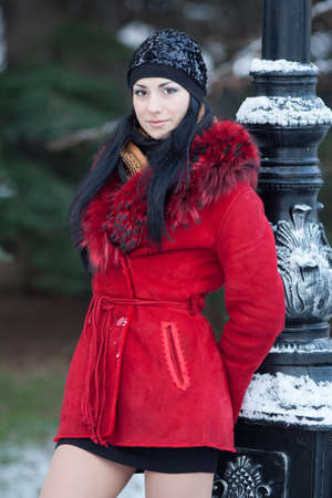 Beautiful young woman at winter. Young beautiful brunette standing near the column, wearing hat, winter timeの写真素材