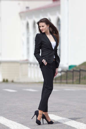 Brunette on stiletto heels outdoors  Young woman in black suit walking along the crosswalkの写真素材