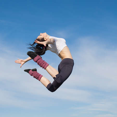 Attractive young woman jumping on open air  Brunette jumps on background of skyの写真素材