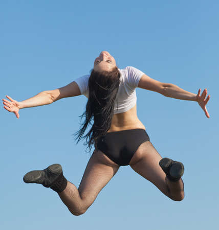 Attractive young woman jumping on open air  Brunette jumps on background of sky