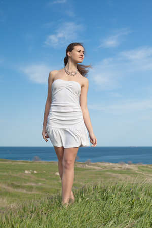 Girl in white on open air  Attractive young woman in white dress walking along fieldの写真素材