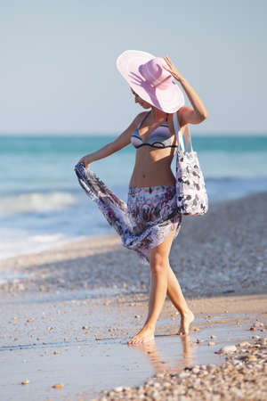 Attractive girl in hat at the sea  Young woman walking along the seashoreの写真素材