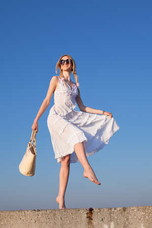 Attractive young woman in white walking  Girl with bag on background of skyの写真素材