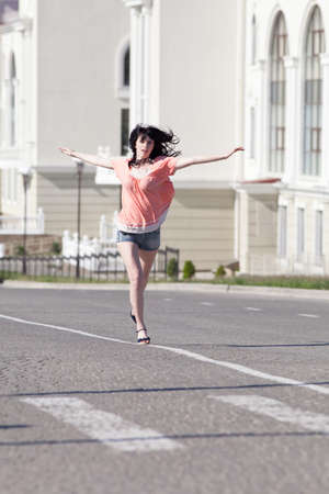 Brunette in shorts on open air. Attractive young woman in shorts running along the carriagewayの写真素材
