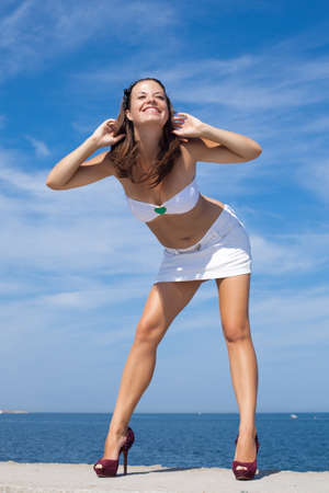 Attractive young woman in white posing outdoors  Girl in white top and skirt on background of skyの写真素材