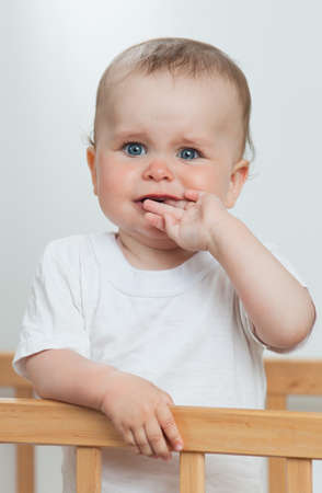 Charming child in the crib  Charming baby is crying looking at cameraの写真素材