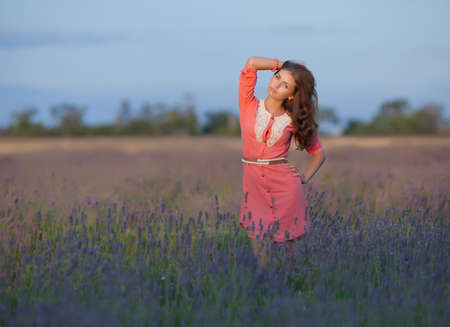Young woman in the field of blossoming lavender. Attractive girl in pink dress posing in field of blooming lavenderの写真素材