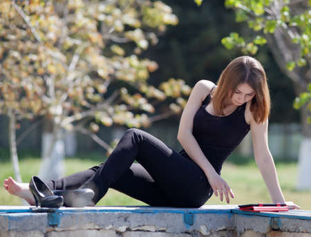 Attractive young woman in the park  Girl uses touchpad on open airの写真素材