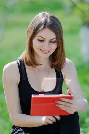 Attractive young woman in the park  Girl uses touchpad on open airの写真素材