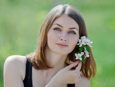 Portrait of attractive young woman on open air  Girl posing with flower of apple  outdoorsの写真素材